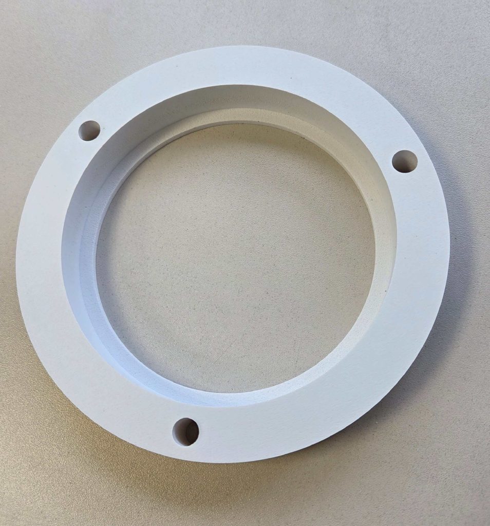 Einzelteilkomponente einer Baugruppe aus SIMOPOR S in 19 mm Stärke. Zu sehen ist ein kreisrundes Stück, mit einer Absatz in einem anderen Durchmesser und 3 Bohrungen.