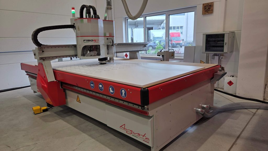 Fräs- und Schneidmaschine F150R Pro von SD Italy mit einer Simopor S-Platte bestückt. Einzelteile einer Baugruppe werden gefräst. Die Hälfte der Platte ist mit Kreisen bereits gefräst, der Rest ist unbearbeitet.